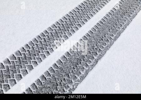Italie, Vénétie, Belluno, Dolomites. Marques de bande de roulement d'un véhicule lourd dans la neige fraîche le long d'une route de montagne Banque D'Images