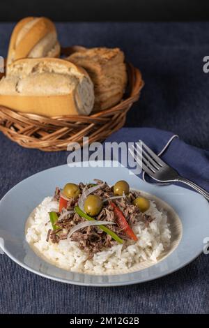 Viande déchiquetée avec du riz et des olives, nourriture typiquement cubaine sur nappe bleue. Banque D'Images