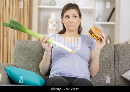 une femme enceinte malheureuse choisit des légumes pour faire du hamburger Banque D'Images