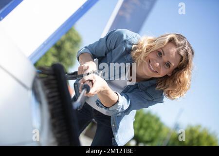 une jeune femme blonde lave sa voiture Banque D'Images