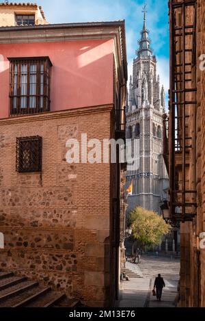 Un homme descend une allée dans la vieille ville de Tolède et la tour de la cathédrale est visible en face de lui. Banque D'Images