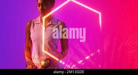 Joueuse de tennis afro-américaine réfléchie avec balle par hexagone et plantes illuminées Banque D'Images