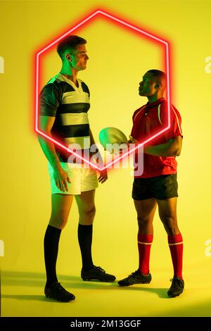 Des hommes multiraciaux de rugby se regardant les uns les autres en illuminant l'hexagone sur fond jaune Banque D'Images