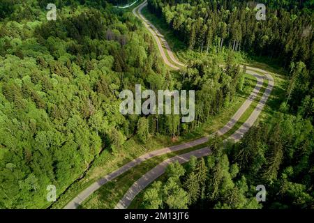 Vue aérienne d'un sentier de ski à roulettes qui s'enroule à travers un paysage forestier, une route asphaltée dans une belle région Banque D'Images