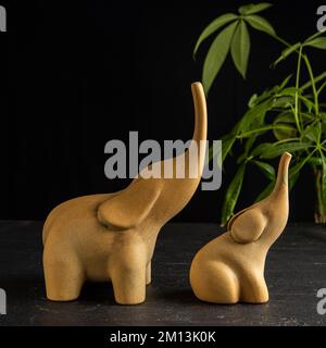 eléphants en céramique jaune objet décoratif sur marbre noir avec plante verte Banque D'Images