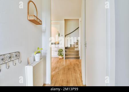 un long couloir étroit avec parquet et murs blancs de chaque côté, il y a une plante dans le coin Banque D'Images