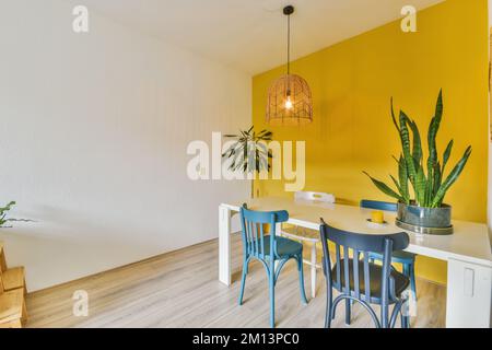 une table à manger et des chaises dans une pièce avec des murs jaunes, du parquet et des murs blancs Banque D'Images