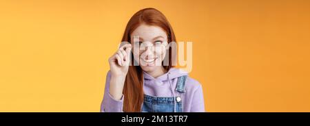 Charmant silly modeste jeune redhead femelle geek jeu amant discus les dernières tendances de jeu souriant joyeusement amusé lunettes de touche grinning curieusement recevoir Banque D'Images