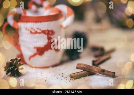 Image floue de tasse de Noël et de bâtons de cannelle sur fond de bois. magnifique effet bokeh dans une guirlande. Banque D'Images