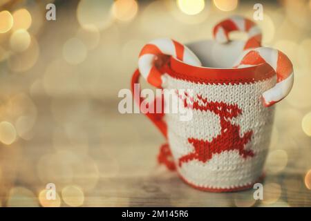 Tasse de Noël et bougie sur fond de bois. magnifique effet bokeh dans une guirlande. Banque D'Images