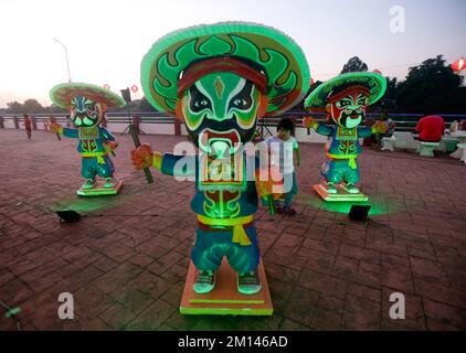 Bangkok, Thaïlande. 10th décembre 2022. Une jeune fille passe devant des statues de 108 la grande danse du guerrier de la montagne Liang Shan pendant le festival Chao Por-Déesse au quartier de CHUM sang, à Bangkok. La grande danse de Liang Shan Mountain, est une danse traditionnelle chinoise combinant la musique, la danse et les arts martiaux réalisés par 108 danseurs qui ont peint leurs visages en différents caractères basés sur l'histoire du troupeau chinois. Le célèbre festival annuel a été créé pour la première fois en 1947 pour respecter le sanctuaire de Chao Por-Déesse. La représentation consiste en une procession d'acteurs défilant autour du district de CHUM sang. Nakhon Sawan Banque D'Images