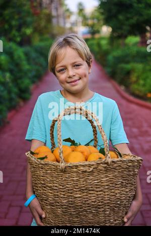 Panier en osier pour garçon caucasien plein de fruits orange frais Banque D'Images