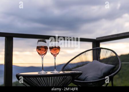 Champagne et cocktails sur table en verre, patio extérieur donnant sur les montagnes au coucher du soleil Banque D'Images