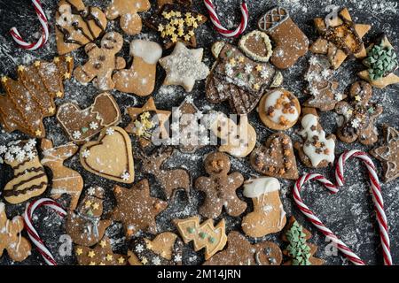 Biscuits de Noël faits maison au pain d'épice avec glaçage ou glaçage, recouverts de farine à pâte. Divers pains d'épice, formes de Noël décorées. Banque D'Images