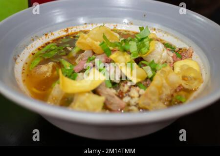 Nouilles jaunes aux œufs dans une soupe épicée de porc, photo de stock Banque D'Images