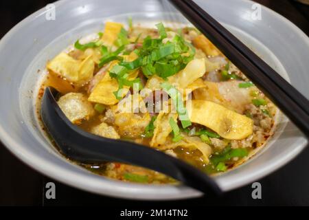 Nouilles jaunes aux œufs dans une soupe épicée de porc, photo de stock Banque D'Images