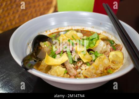 Nouilles jaunes aux œufs dans une soupe épicée de porc, photo de stock Banque D'Images