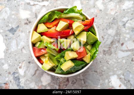 Salade d'avocats et de tomates fraîches dans un bol sur fond de pierre grise vue de dessus. Concept alimentaire pour les Parties. Restauration rapide. Déjeuner sain. Livraison de nourriture en dispo Banque D'Images