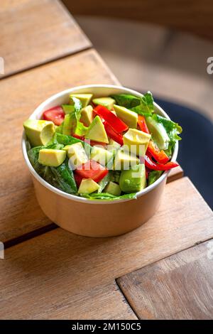 Salade d'avocats et de tomates fraîches dans un bol, vue du dessus. Concept alimentaire pour les Parties. Restauration rapide. Déjeuner sain. Livraison de nourriture dans une assiette jetable de Craft pap Banque D'Images