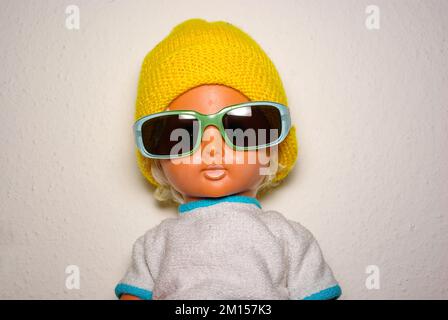 Poupée élégante avec lunettes de soleil et casquette tricotée jaune, jouet pour enfants de la RDA du 1970s, concept de jeu enfantin et d'expression humaine. Banque D'Images