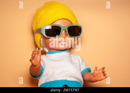 Poupée élégante avec lunettes de soleil et casquette tricotée jaune, jouet pour enfants de la RDA du 1970s, concept de jeu enfantin et d'expression humaine. Banque D'Images