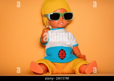 Poupée élégante avec lunettes de soleil et casquette tricotée jaune, jouet pour enfants de la RDA du 1970s, concept de jeu enfantin et d'expression humaine. Banque D'Images