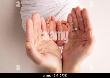 Jambes, orteils, pieds et talons d'un nouveau-né. Les mains des parents tiennent les jambes de l'enfant Banque D'Images