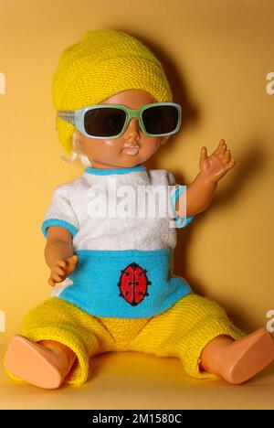 Poupée élégante avec lunettes de soleil et casquette tricotée jaune, jouet pour enfants de la RDA du 1970s, concept de jeu enfantin et d'expression humaine. Banque D'Images