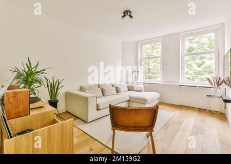 une salle de séjour avec murs blancs et parquet, il y a une grande fenêtre qui donne sur les arbres à l'extérieur Banque D'Images