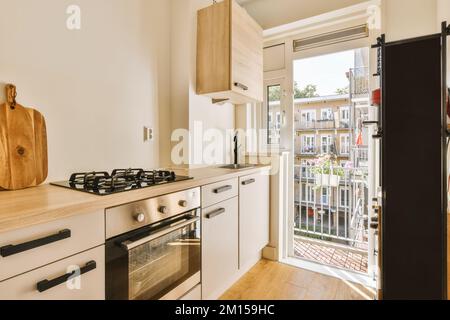 une cuisine avec une porte ouverte menant à la terrasse et vue extérieure par la porte coulissante en verre qui mène au balcon Banque D'Images