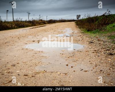 route boueuse sur une route rurale inondée par les pluies hivernales Banque D'Images