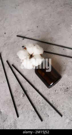 Bouteille transparente de diffuseur d'arôme. Parfum pour la maison avec fleurs de coton. Concept tendance, matériaux naturels. Photo verticale sur fond de marbre Banque D'Images