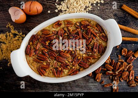 Flocons d'avoine cuits avec pacanes confites sur une table en bois : tarte aux pacanes flocons d'avoine cuits dans un plat de cuisson ovale en céramique Banque D'Images