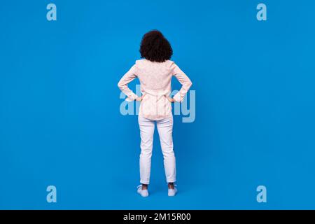 Portrait arrière pleine grandeur d'une personne sûre de mettre les mains à la taille isolée sur fond bleu Banque D'Images