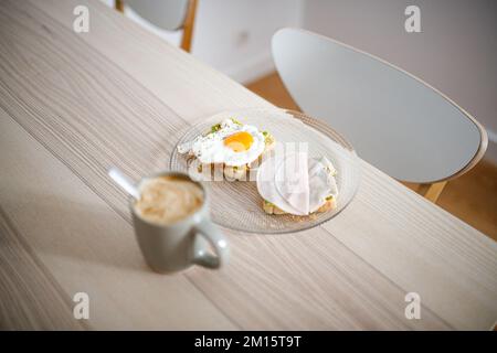 Un grand angle de délicieux sandwichs à base d'œufs frits et de jambon placés sur une table en bois avec une tasse de café chaud Banque D'Images