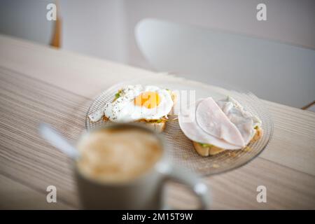 Un grand angle de délicieux sandwichs à base d'œufs frits et de jambon placés sur une table en bois avec une tasse de café chaud Banque D'Images