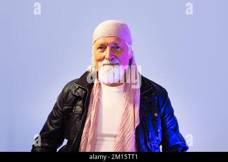 Homme senior barbu en cuir veste et bandana regardant l'appareil photo sur fond blanc Banque D'Images