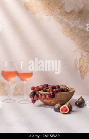 Verres de boisson rouge placés sur la table avec un bol de raisins et de figues Banque D'Images
