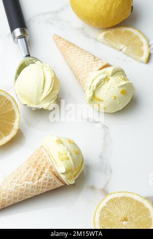 Au-dessus des cornets de gaufres et une cuillère avec une délicieuse glace maison placée sur une table en marbre avec des tranches de citron à la lumière du jour Banque D'Images