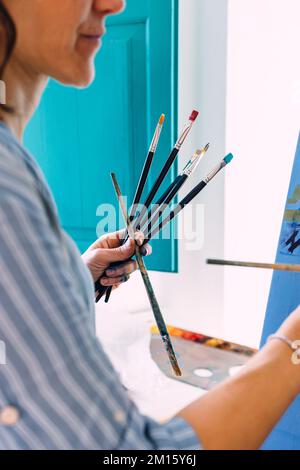 Rognez une artiste féminine anonyme qui peint de la peinture colorée sur toile tout en travaillant en studio créatif Banque D'Images