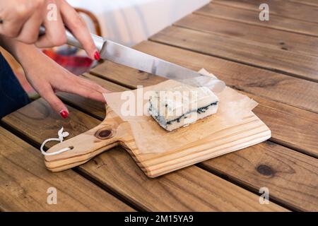 Coupe féminine anonyme à grand angle avec une barre porte-guillotine de savon à la main sur une planche à découper en bois Banque D'Images