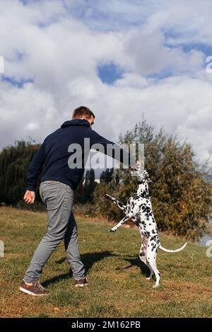 beau jeune homme avec chien à l'extérieur. un homme sur l'herbe verte avec un chien. cynologue Banque D'Images