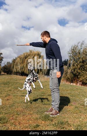 beau jeune homme avec chien à l'extérieur. un homme sur l'herbe verte avec un chien. cynologue Banque D'Images