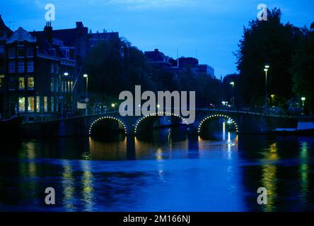 Amsterdam Hollande le Torensluis l'un des ponts les plus anciens et les plus larges de la ville illuminé la nuit au-dessus du canal Singel Banque D'Images