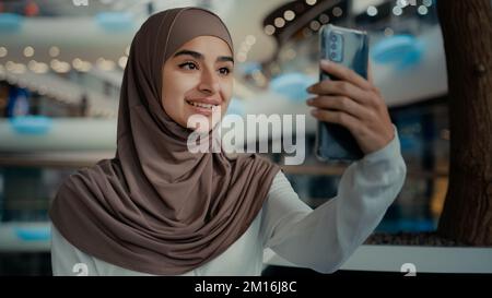 Islamique musulmane dame belle femme dans hijab tenir moderne gadget parler téléphone regarder la webcam chatter en ligne mobile vidéo appel arabian fille shopper Banque D'Images