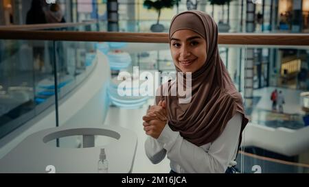 Une jeune fille étudiante islamique se nettoie les mains par assainisseur au café public une femme arabe dans le hijab soins de santé utiliser un spray antibactérien du coronavirus Banque D'Images