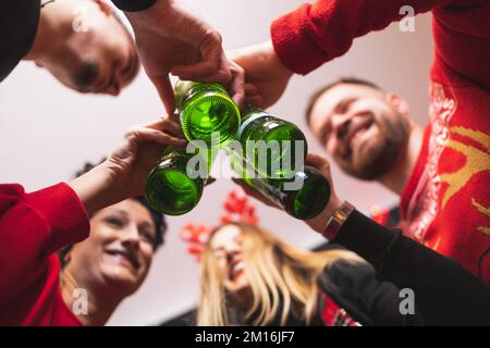 Quatre amis fêtent le nouvel an avec des bouteilles de bière. Concentrez-vous sur les flacons Banque D'Images