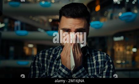 Malade arabian man jeune homme allergique gars dans le centre commercial souffrent de nez liquide grippe maladie saisonnière allergie couverture bouche éternuer essuyer nez avec Banque D'Images