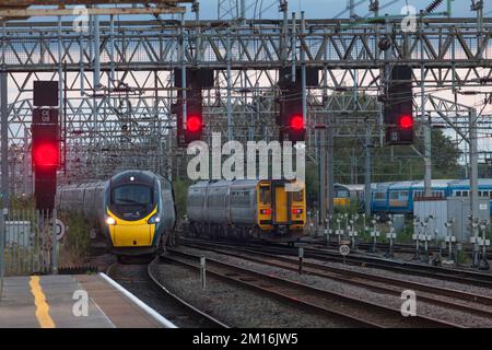 Avanti West Coast Pendolino train et transport pour le sprinter du pays de Galles en passant à la jonction sud de Crewe avec des signaux rouges sur un portique Banque D'Images