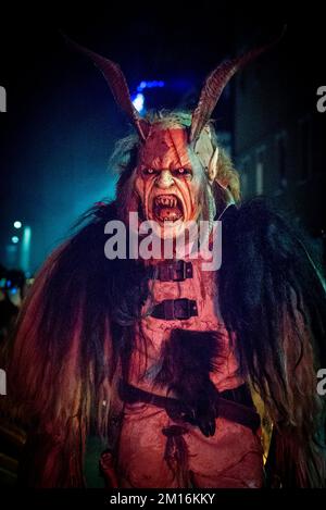 Les monstres masqués de diable défilent dans le village en écartant la foule tout en gardant vivante cette tradition alpine folklorique Banque D'Images